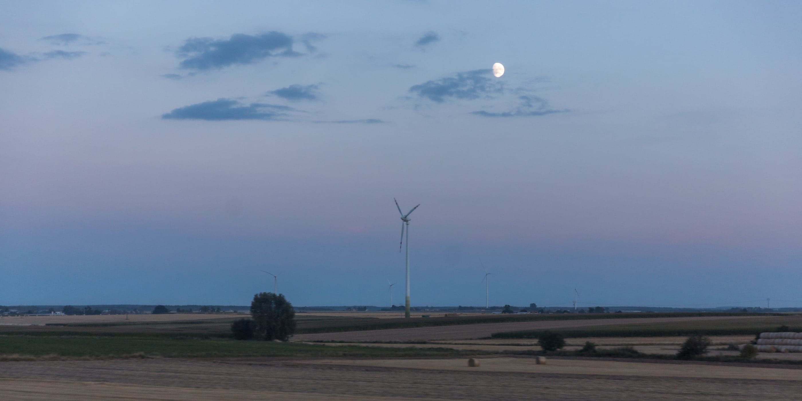 Wind turbines over open farmland at dusk on the drive east