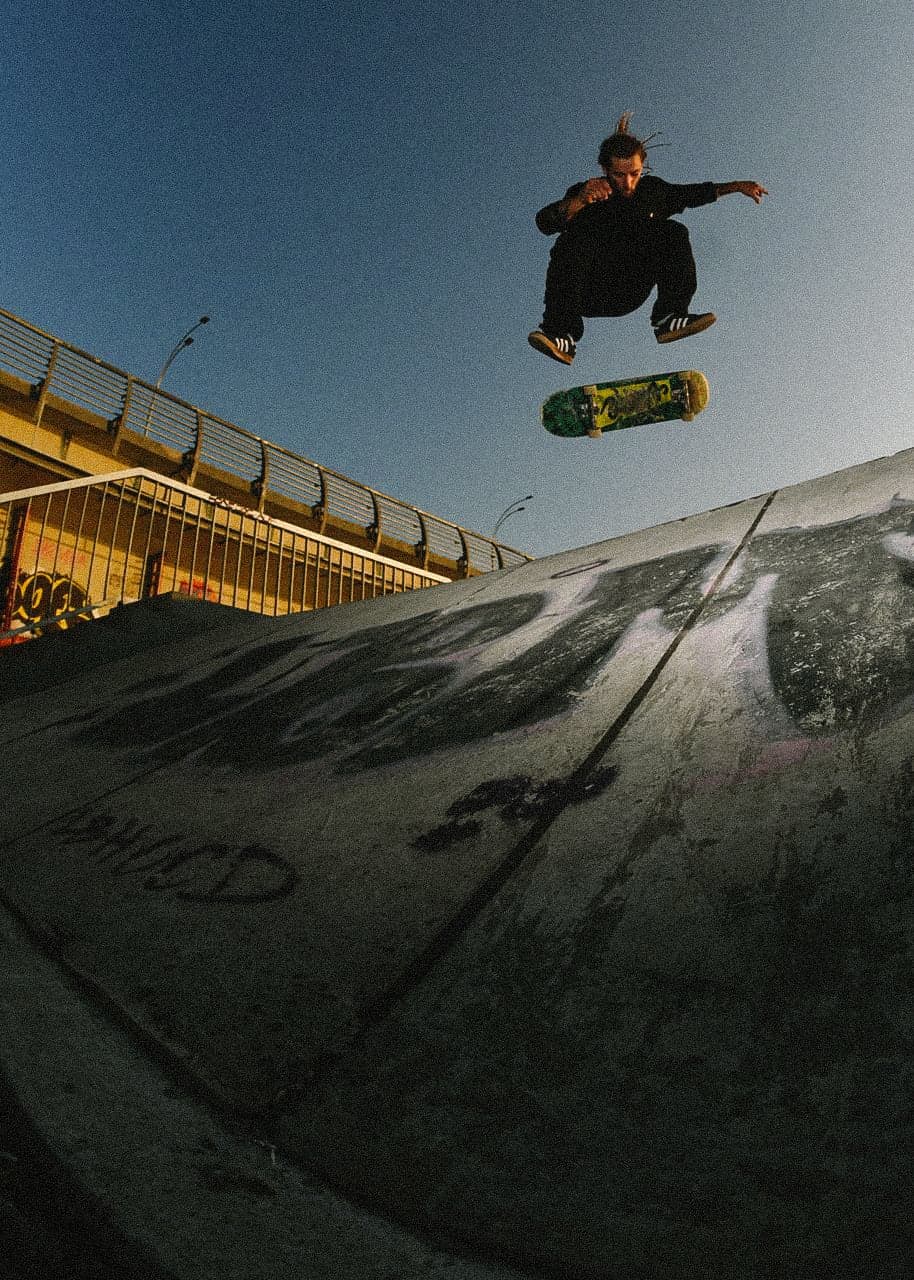 Skateboarder floating a trick high above a concrete bank at dusk