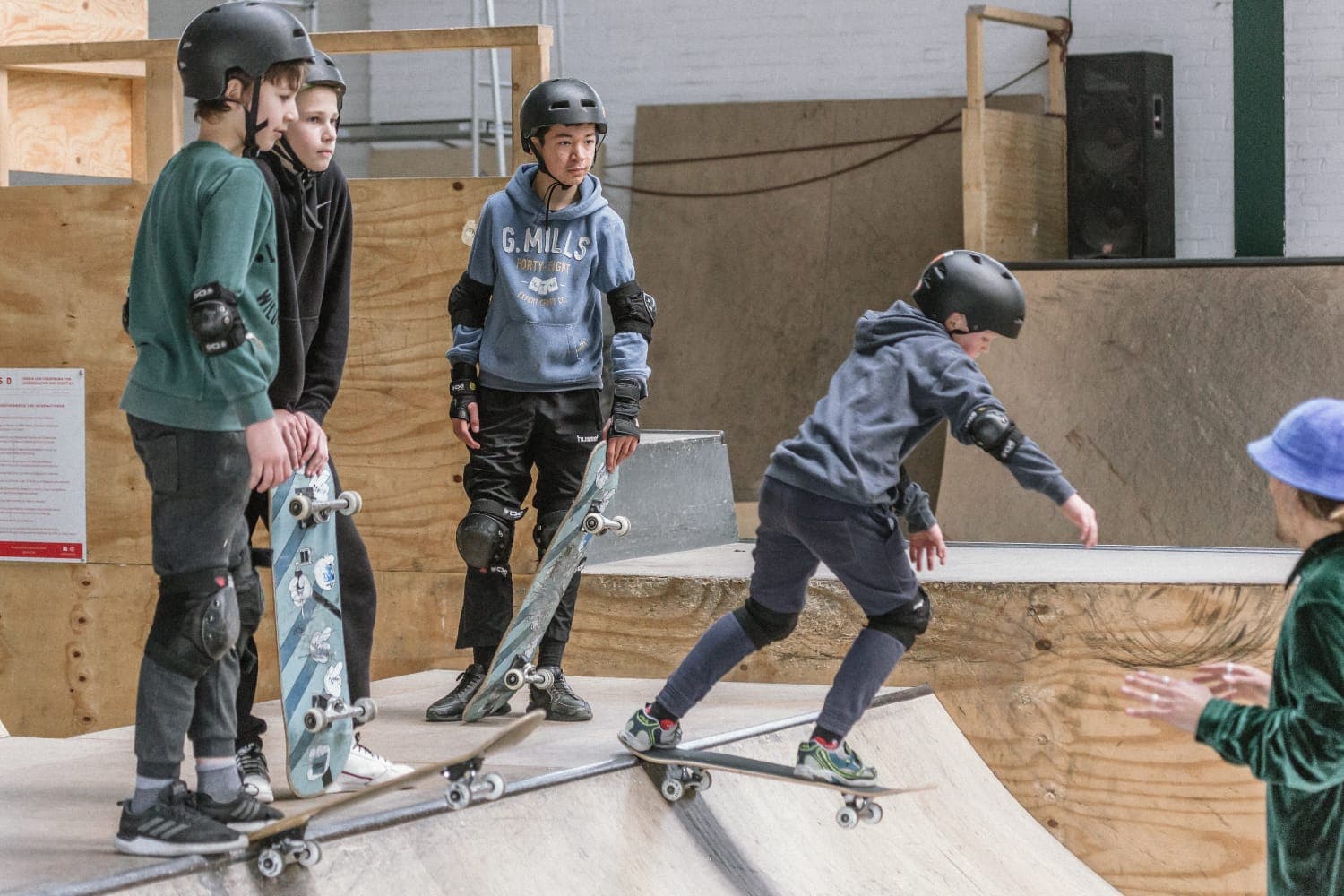Students waiting their turn on the ramp as another rolls in at the indoor skatehalle