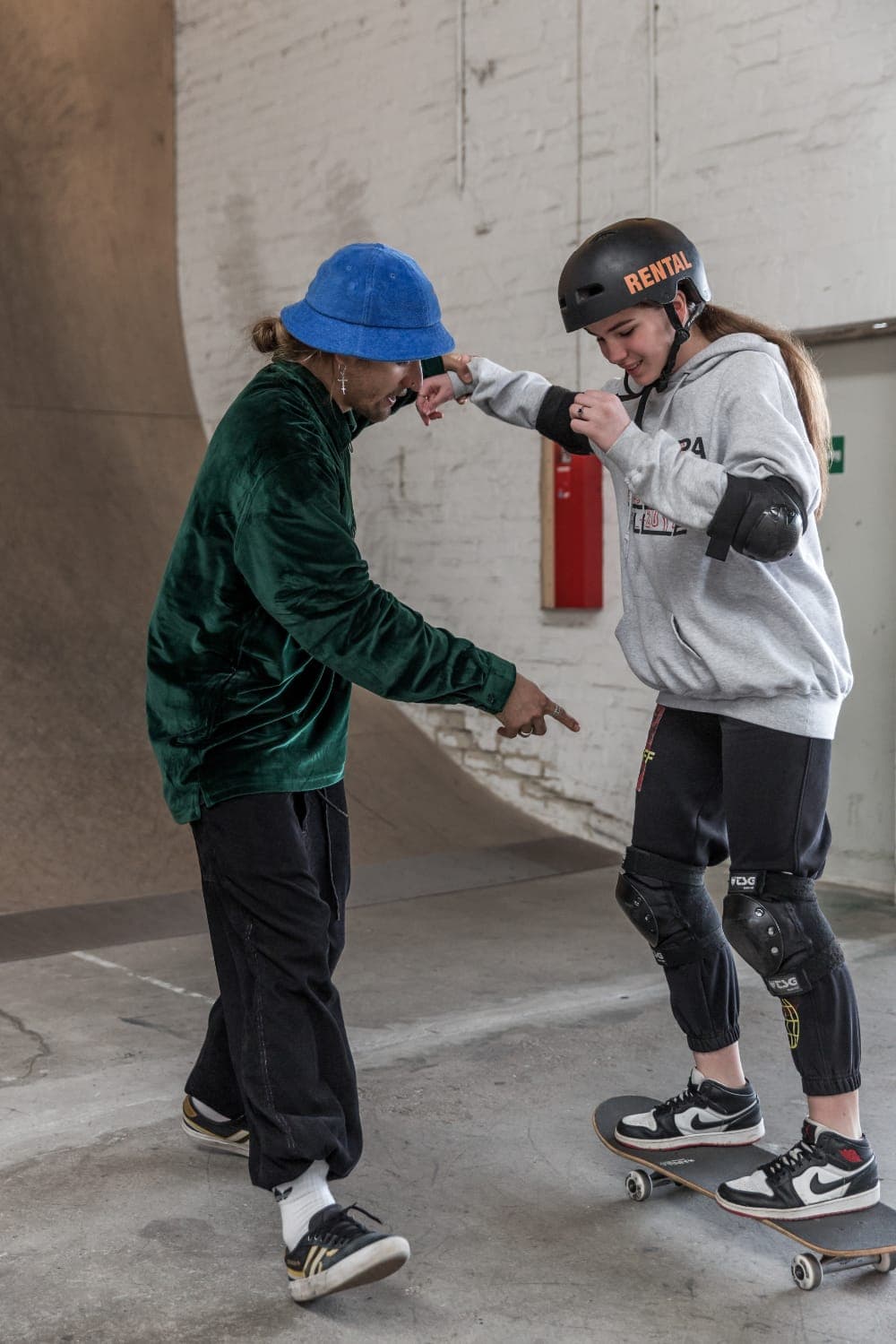 Coach talking a student through her stance on the board at the indoor skatehalle in Hannover